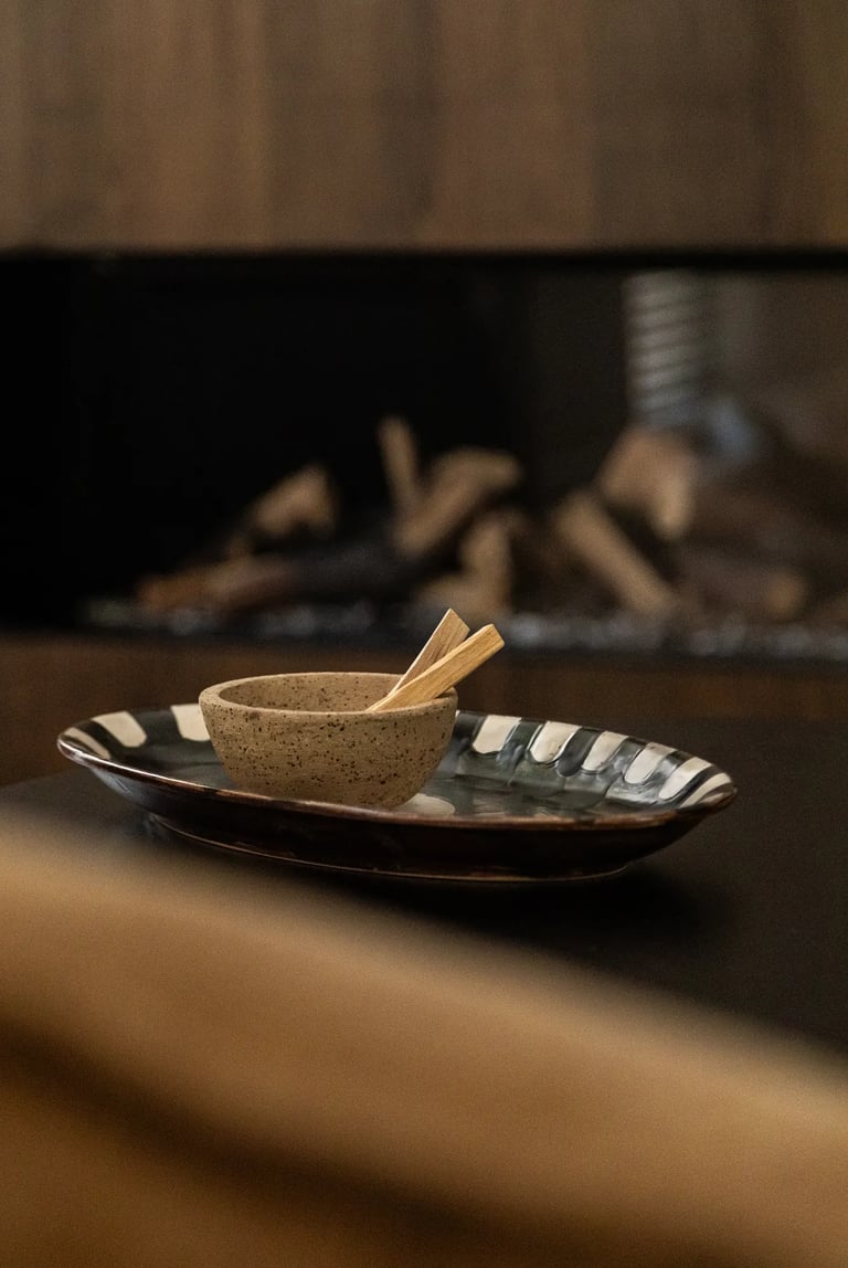 Kompozycja zdjęcia: detal stolika kawowego, ceramika i palo santo.