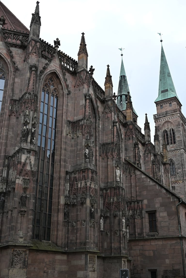 Gothic architecture of St. Sebaldus Church in Nuremberg featuring ornate stone carvings and green spires.