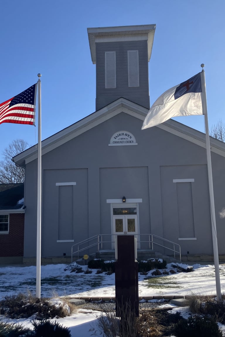 gray country church with flags in the foreground