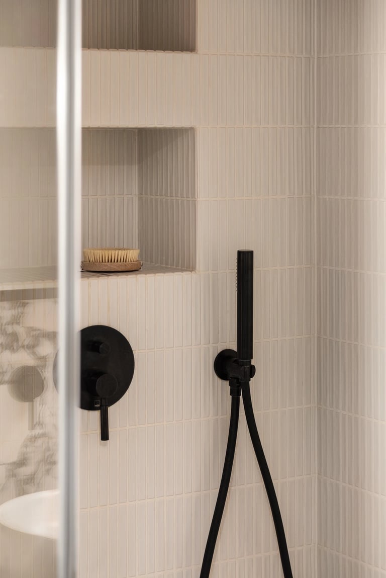 Zbliżenie na armaturę: wnęka prysznicowa i czarna bateria.