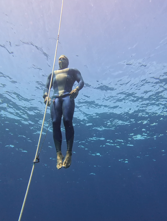 A Freediver using buoyancy to ascend towards the surface along a dive line