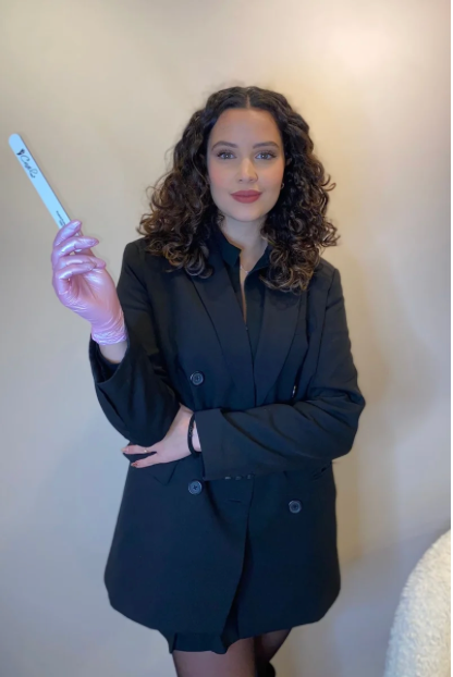 a woman in a black suit and gloves holding a toothbrush