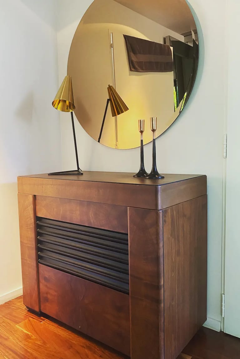 Mueble de diseño, espejo redondo y lámparas de diseño componiendo un espacio único y con clase.