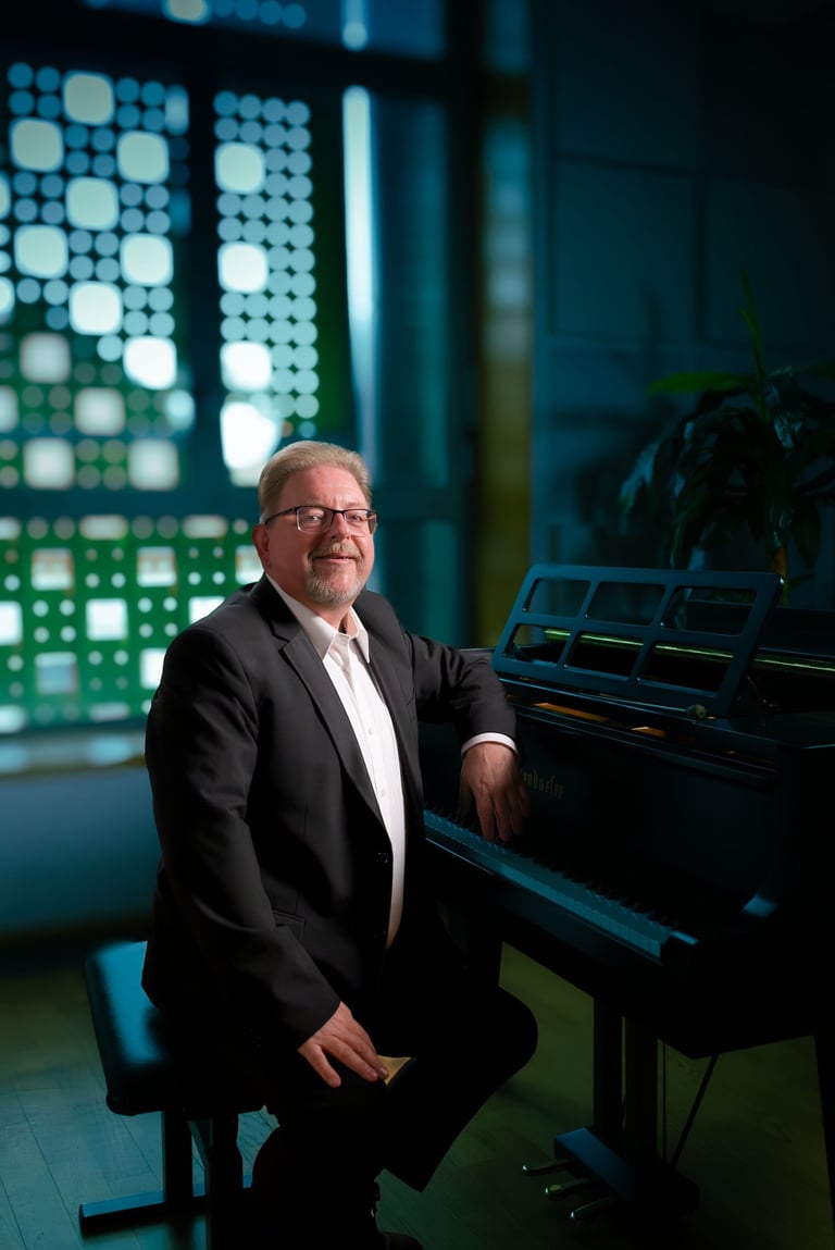 Robert in a suit and tie is sitting at a piano