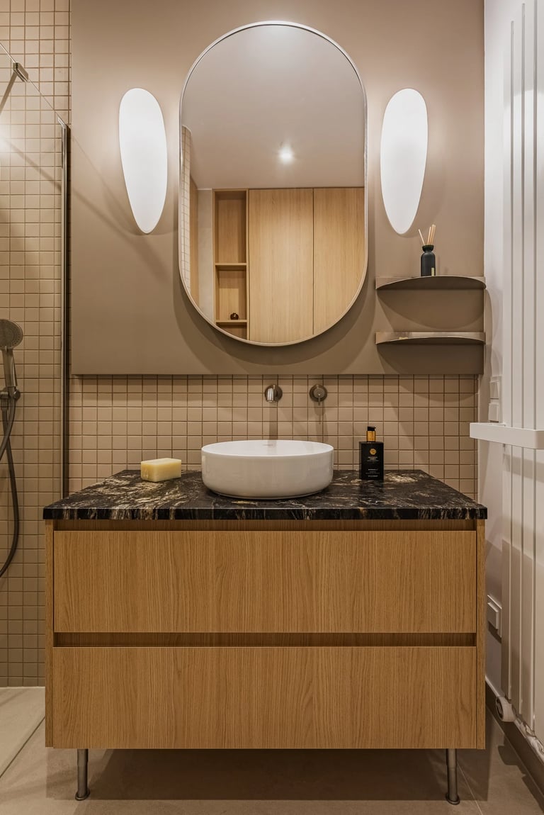 Fotografia wnętrz łazienki: umywalka nablatowa, kamienny blat i beżowe kafelki kwadratowe.