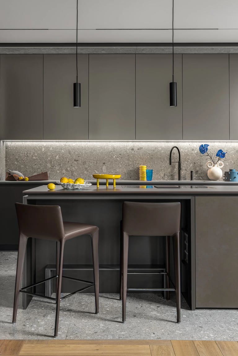 Grafitowa zabudowa kuchenna z oświetleniem LED, nowoczesne hokery i ściana z lastryko.