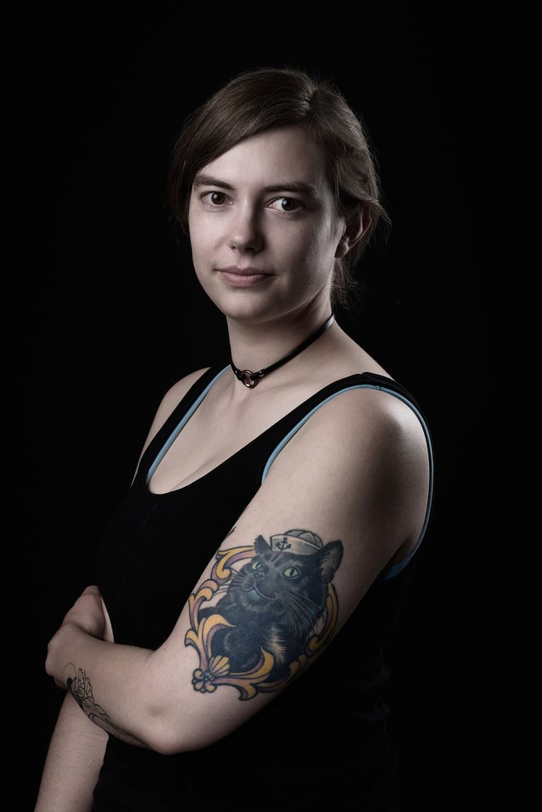 a woman with cat tattoo on her arm in front of a black background