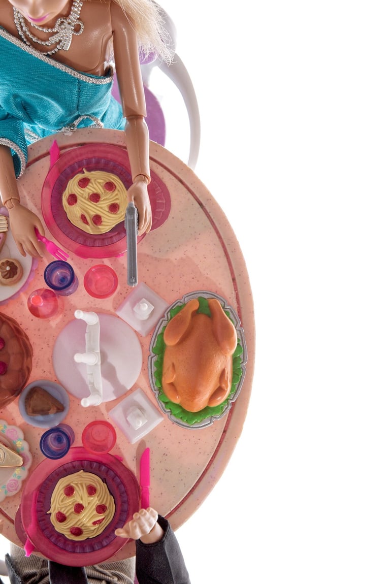 a doll sitting at a table with a doll