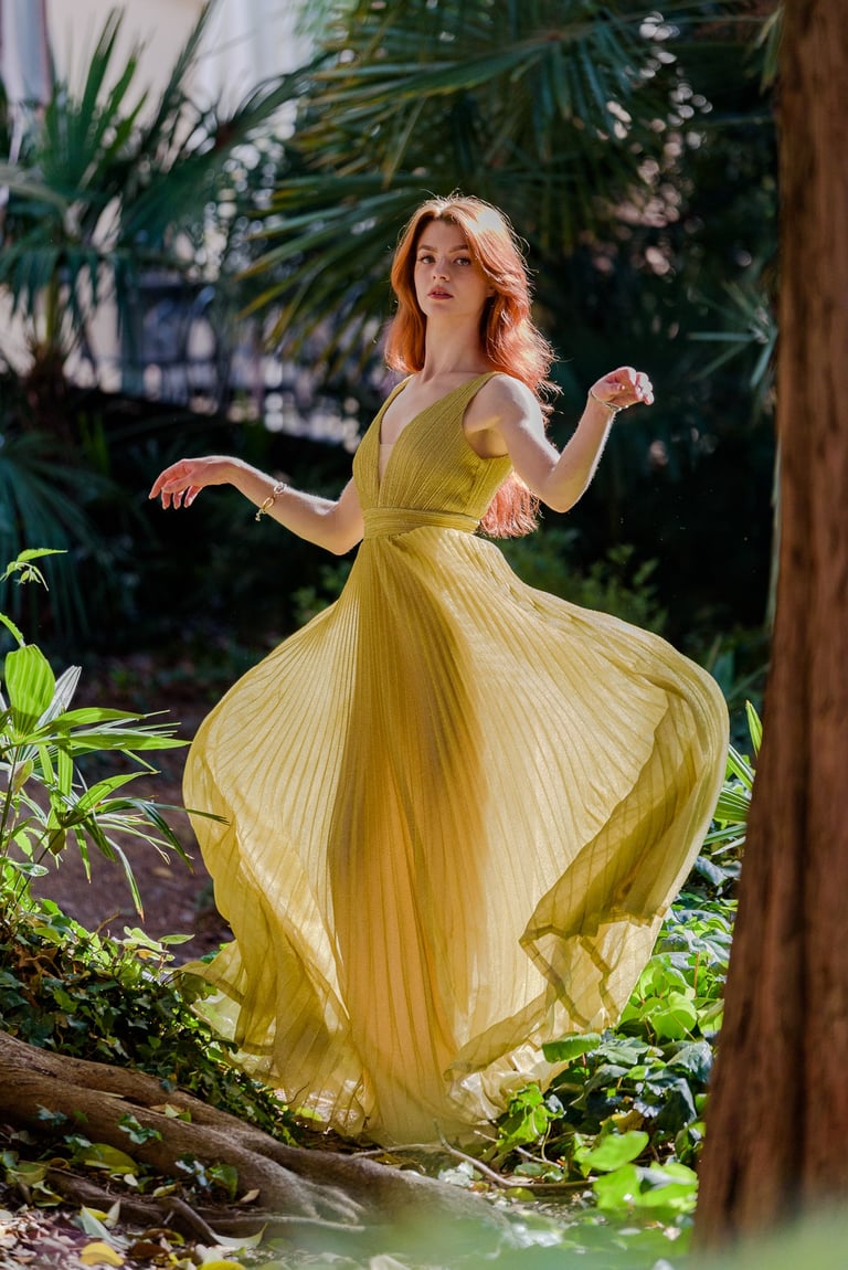 Ragazza in mezzo alla vegetazione con un abito dorato svolazzante