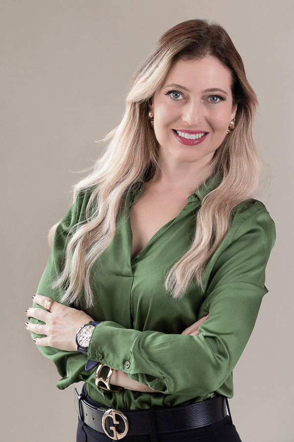 mulher loira, empresário com braços cruzados e sorrindo para a foto em fundo rosé