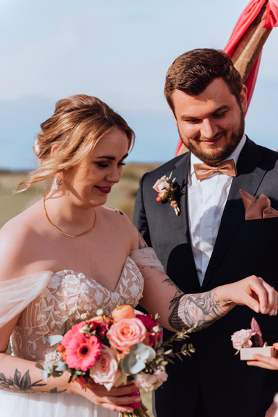 Ringtausch. die tätowierte Braut greift nach dem Ehering um diesen ihrem Bräutigam anzustecken. er lächelt glücklich