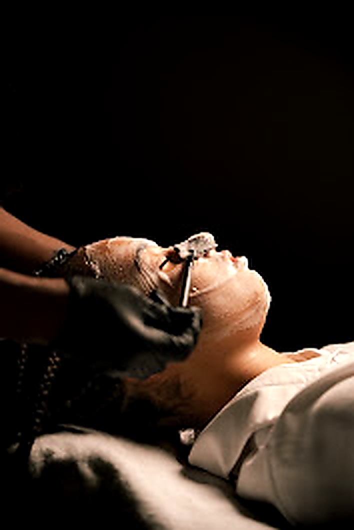 Jeune femme qui se fait appliquer un masque par une esthéticienne