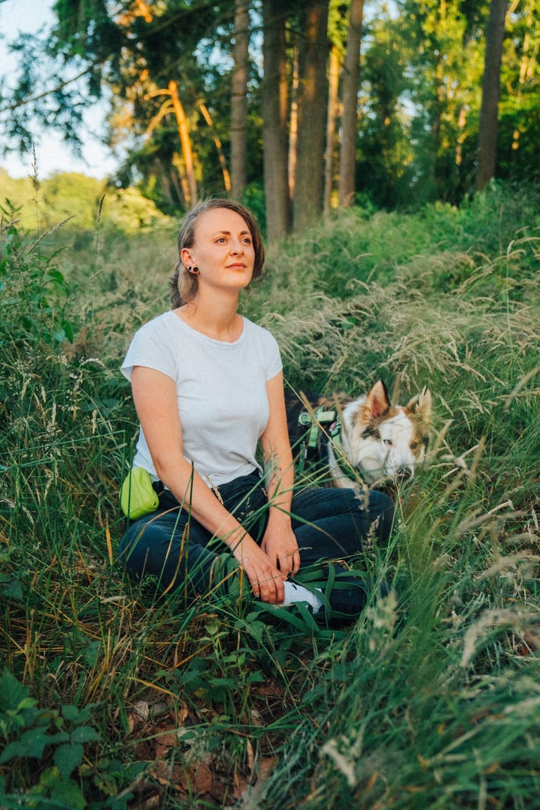 Toni sitzt mit Hund im Wald und blickt ruhig in die Ferne – Stille und Verbindung im Waldbaden