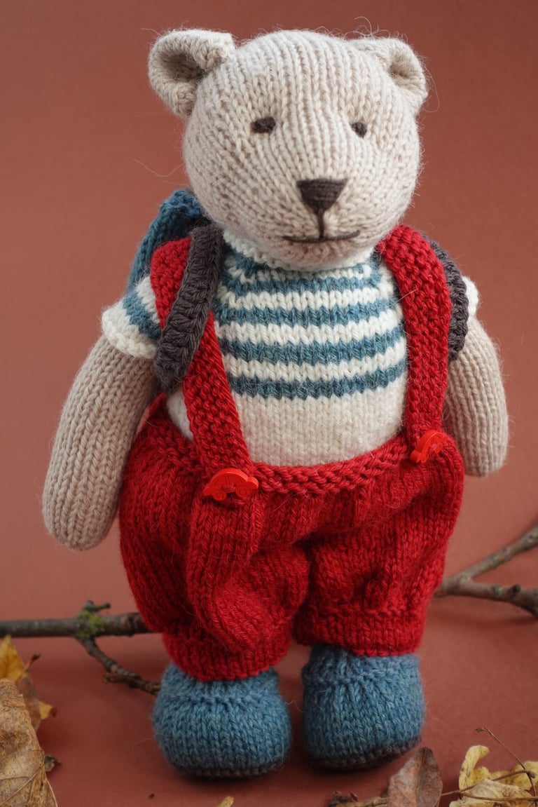 a teddy bear in a knitted sweater and overalls