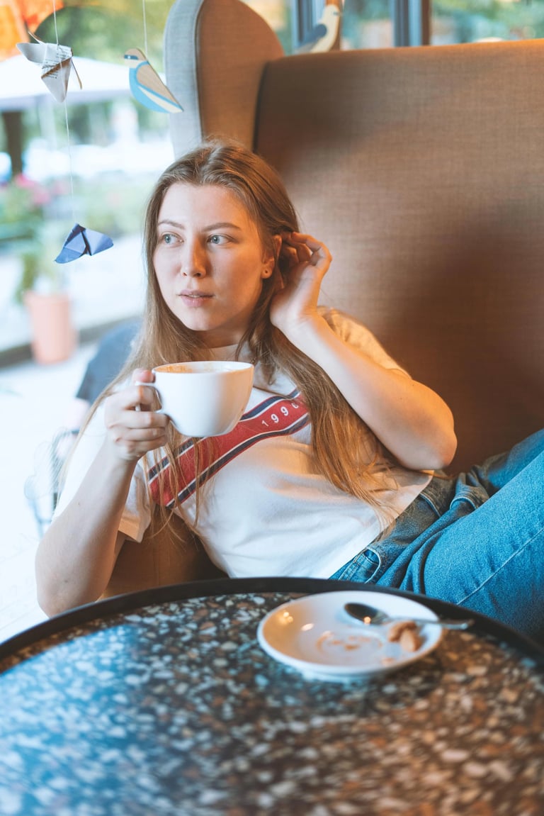 90s style portait picture of a young girl in a coffee shop drinking coffee in a big armchair  