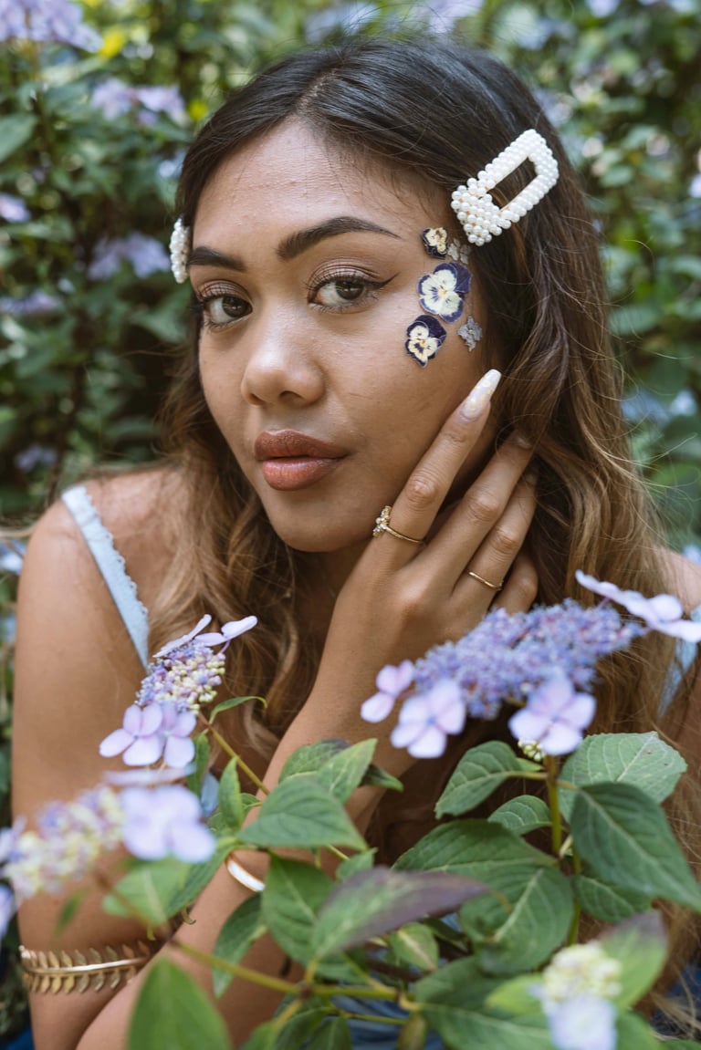 Portrait photo of a young Indonesian woman in a park with flowers and whimsical blue dress