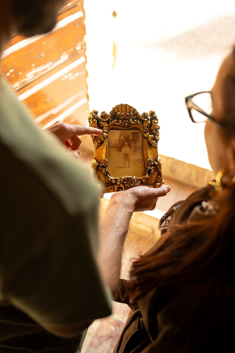 A person holding an ornate gold vintage frame with an old black and white photograph.