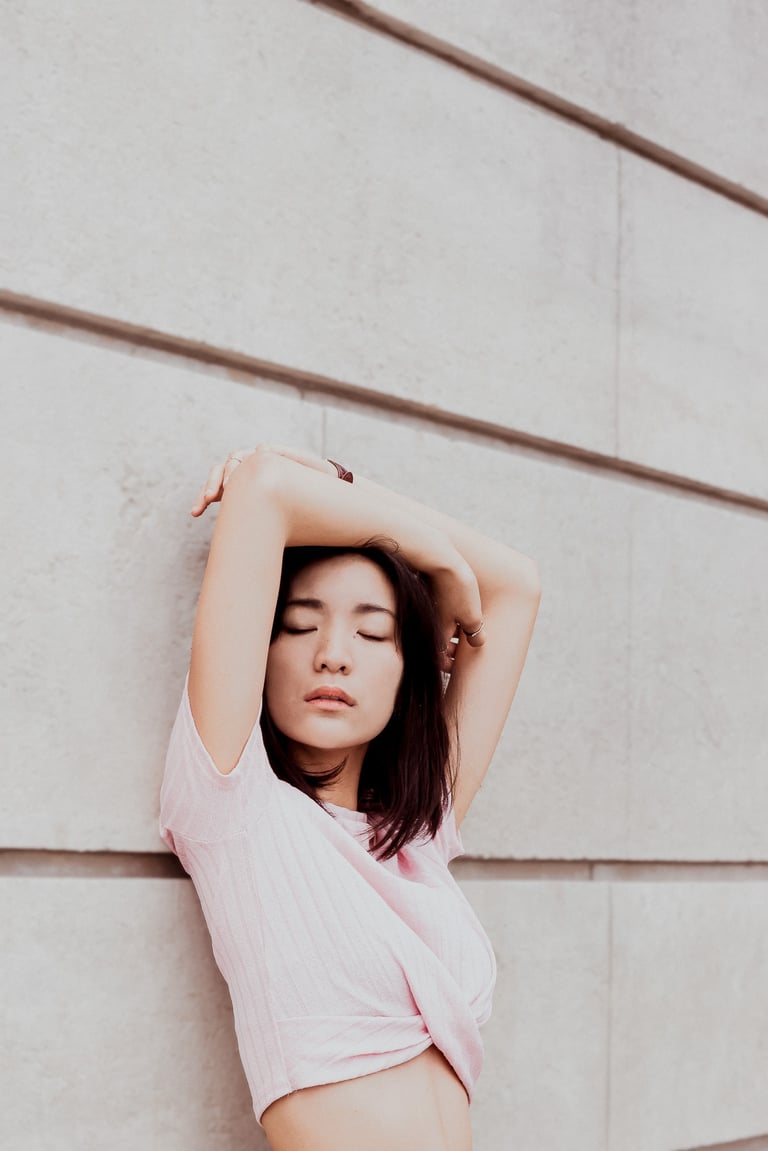 portrait de femme les mains au dessus de la tête adossée contre un mur