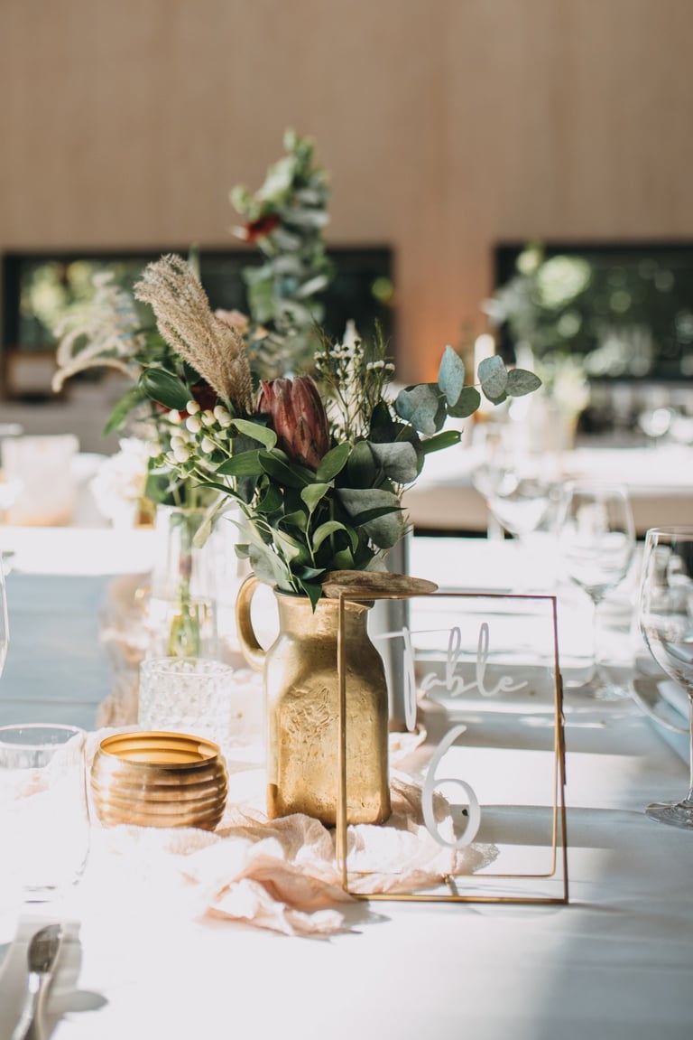 Dekortierter Tisch mit goldener Vase und Protea