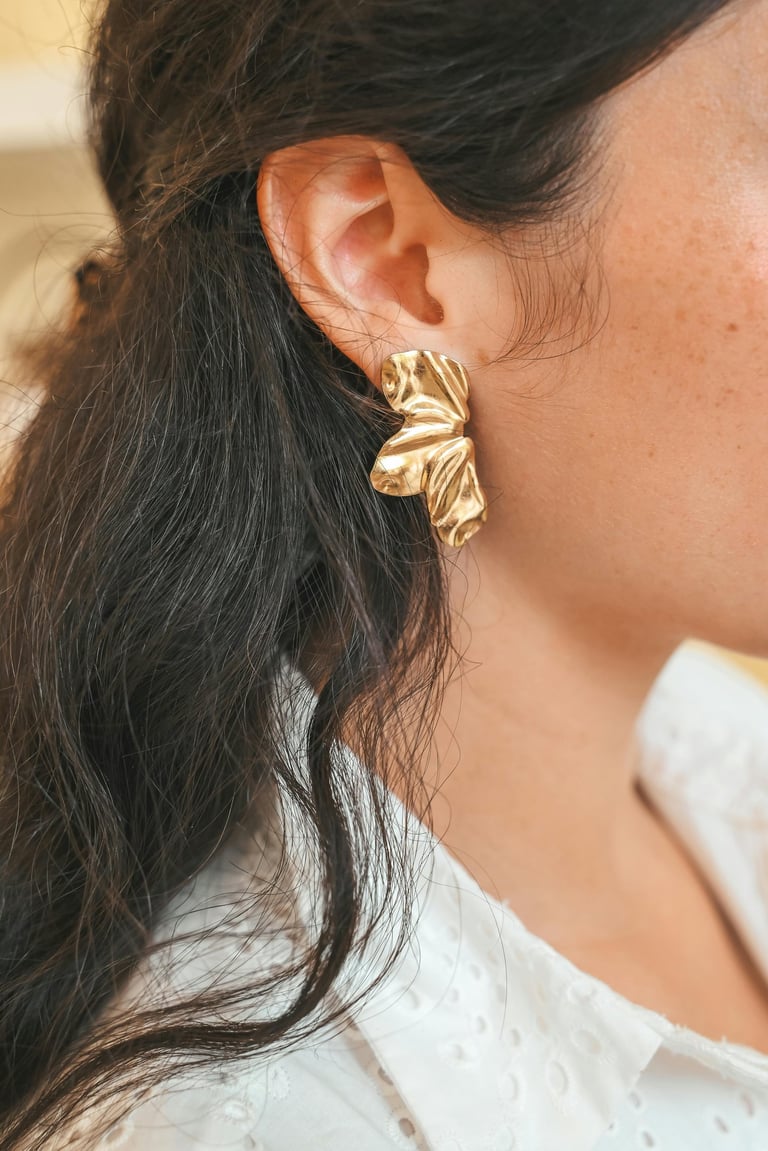 Stilingi aukso spalvos auskarai su unikalia tekstūra. Modernus ir ryškus papuošalas, suteikiantis įvaizdžiui elegancijos.