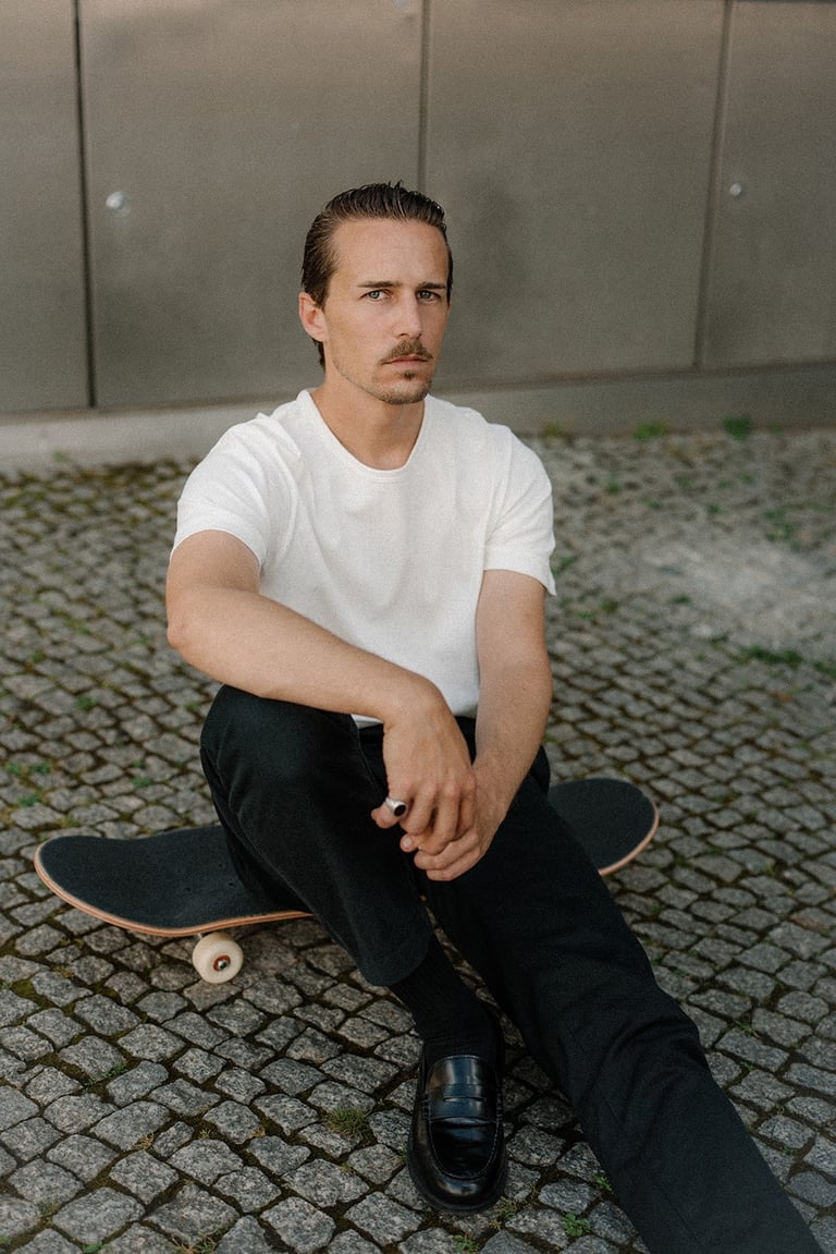 Portrait of artist and designer Philipp Schäfer sitting on a skateboard
