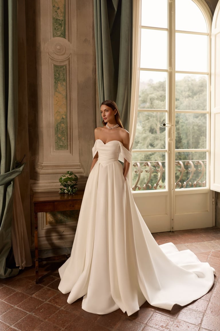Elegant bride in an off-the-shoulder ball gown wedding dress with a sweetheart neckline.
