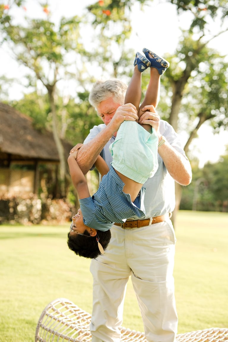 grandfather lifting his grandchild in warm sunset light at rimba by ayana bali during joyful bali family photography