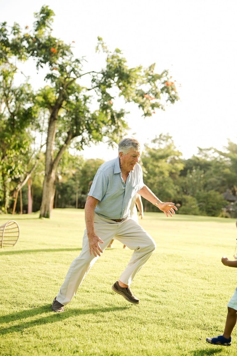 grandfather playing and running with his grandchildren on the lawn at rimba by ayana bali a candid family photography moment