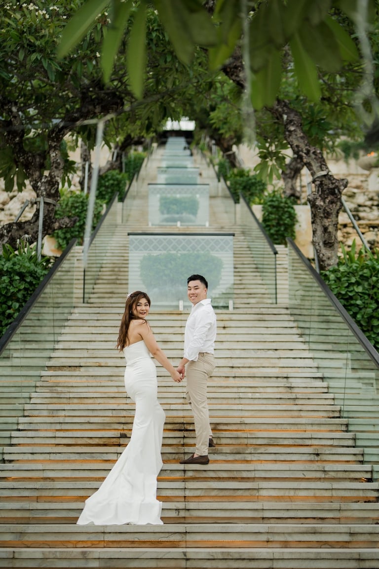 Couple posing together on the grand staircase during a prewedding photoshoot at Apurva Kempinski Bali
