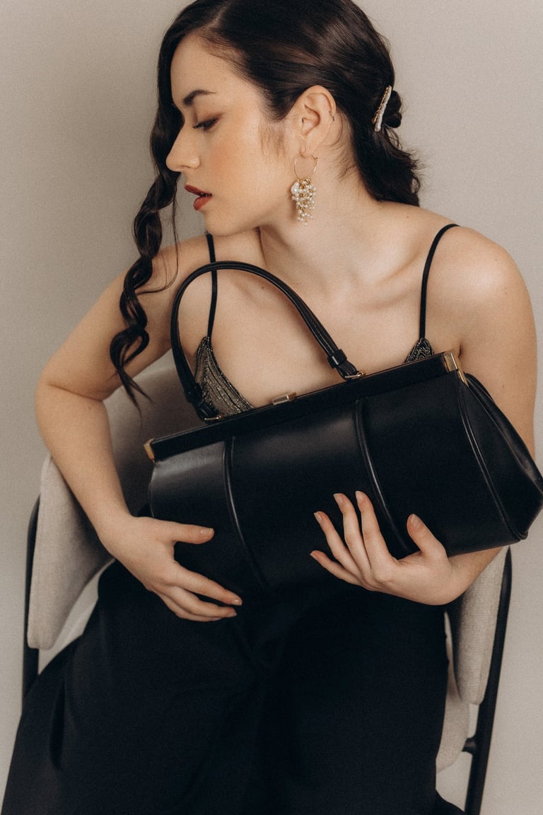 a woman in a black dress holding a black purse