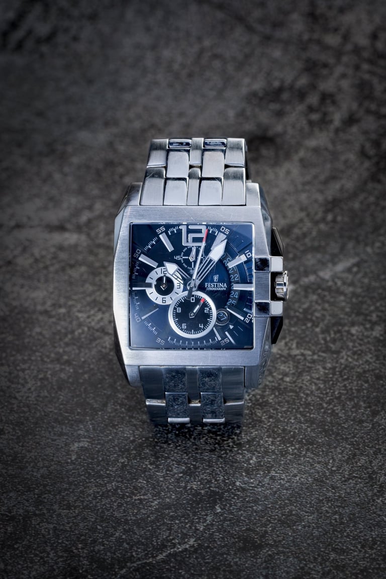 Montre argentée de marque Festina, cadran bleu sur fond pierre noire