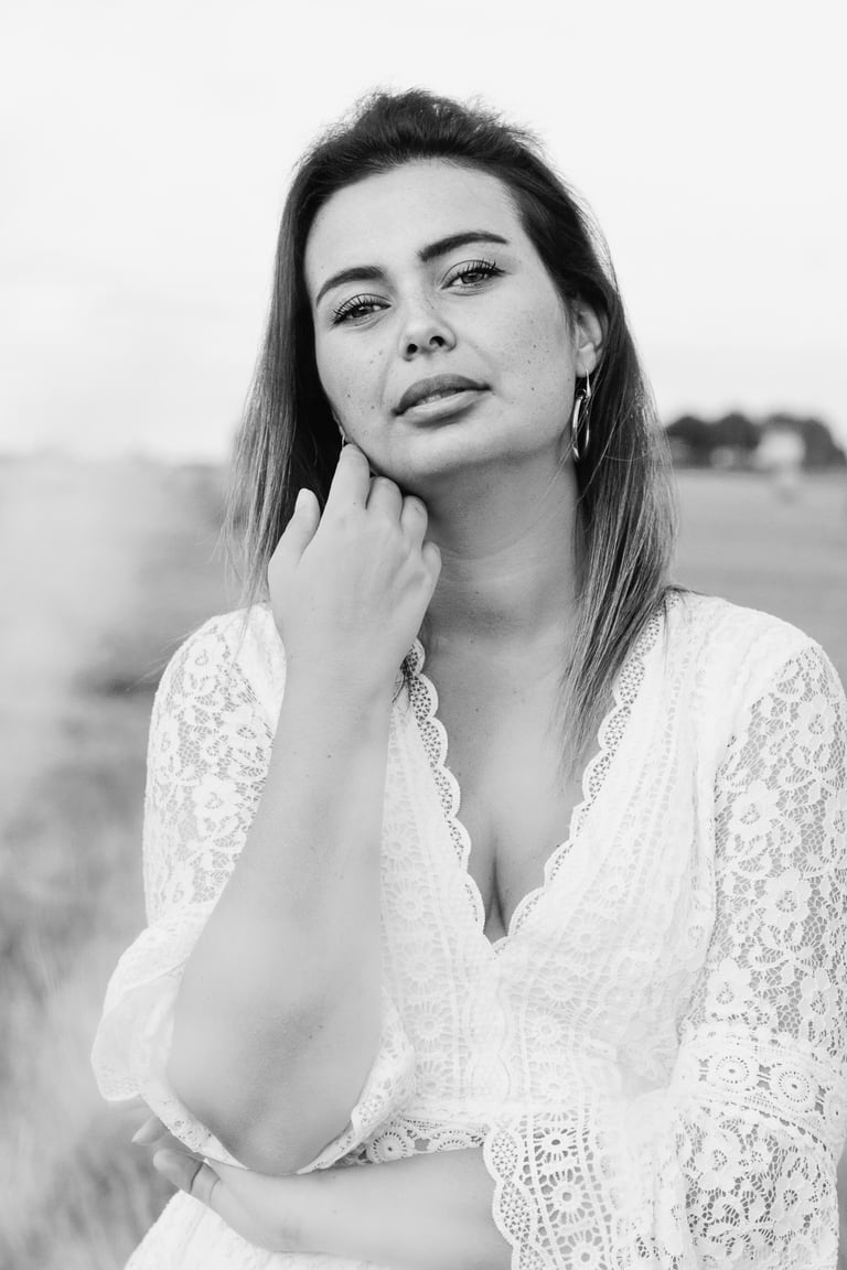 portrait féminin en noir et blanc se caressant la joue et regardant l'objectif en extérieur