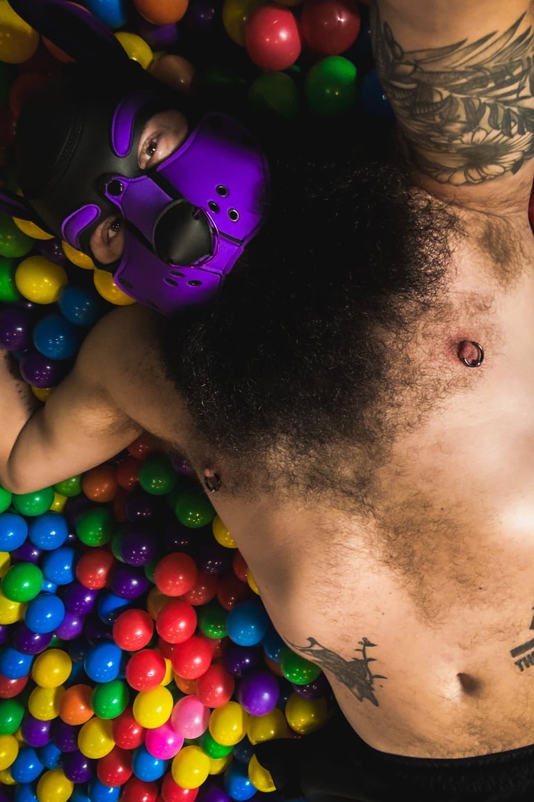 Man in pup mask lying in a ball pit.