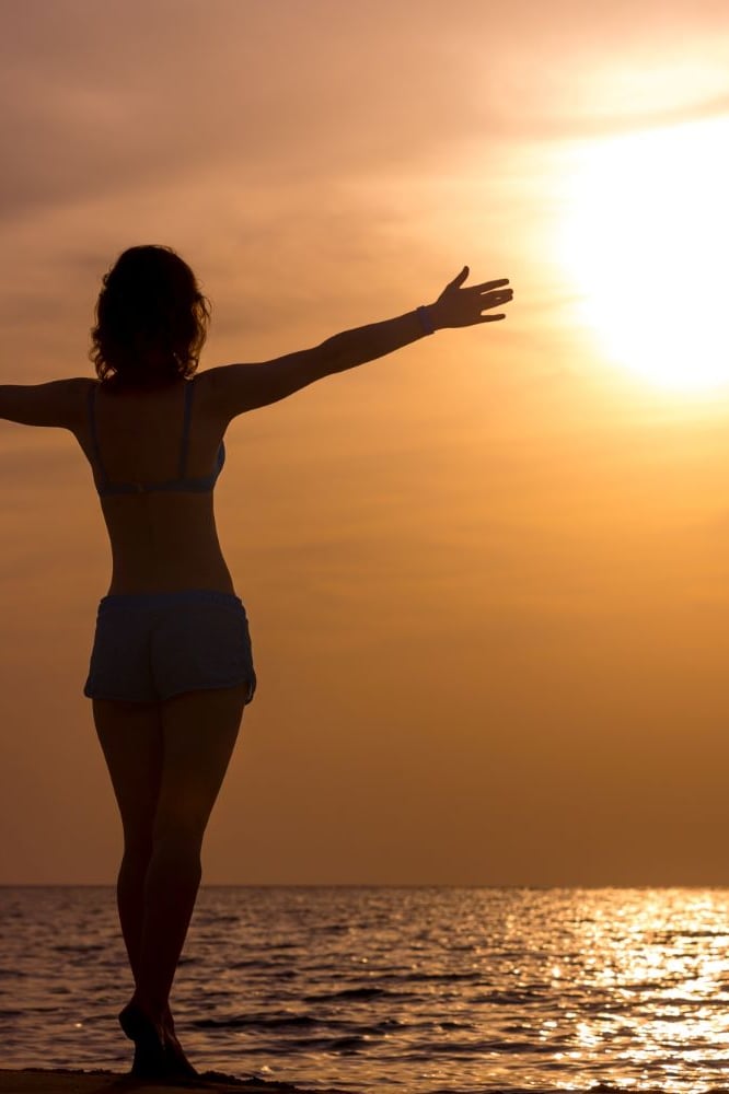 femme libre et heureuse et sereine qui regarde l'horizon en levant les bras