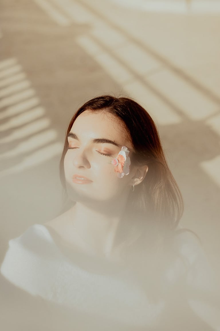 portrait féminin fermant les yeux maquillé avec des fleurs couleurs douces premier plan flou