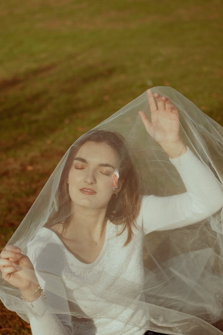 plan éloigné d'un visage féminin fermant les yeux et recouvert d'un voile en tulle transparent