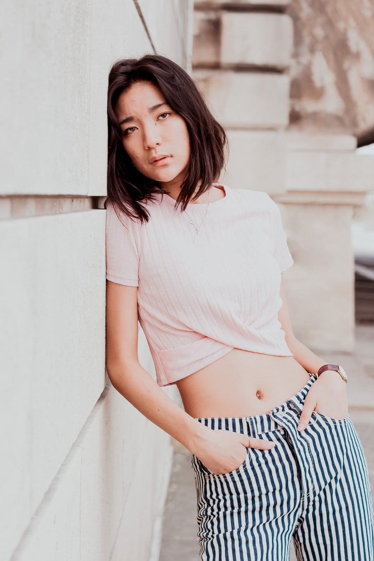 portrait de femme adossée contre un mur en pierreregardant l'objectif couleurs douces