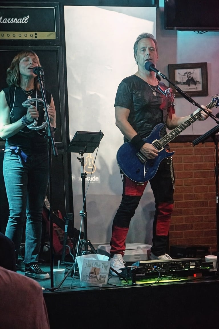 Live band performance featuring a female singer with a tambourine and a male guitarist on stage.