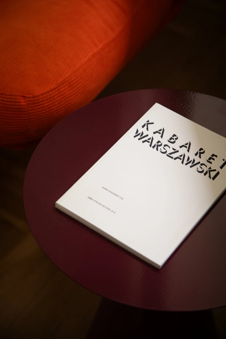 Minimalistyczny detal: kontrast bieli albumu i bordowego stolika.