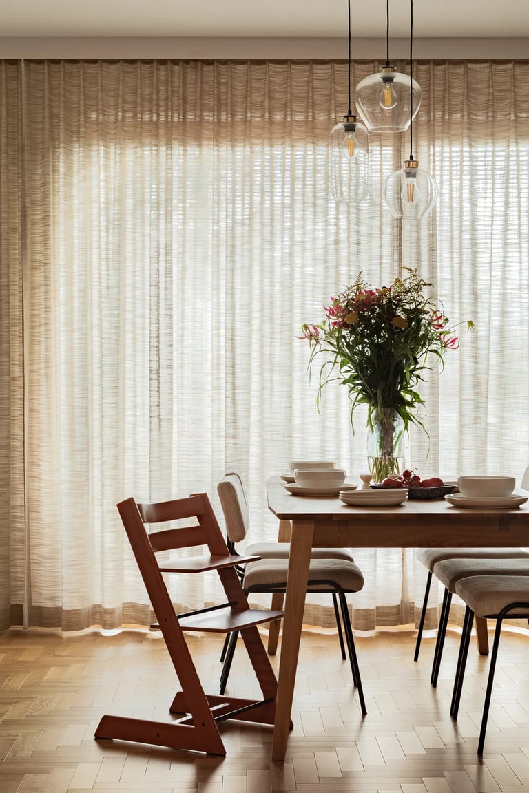 Pionowy kadr: naturalne światło w jadalni i krzesło dziecięce.