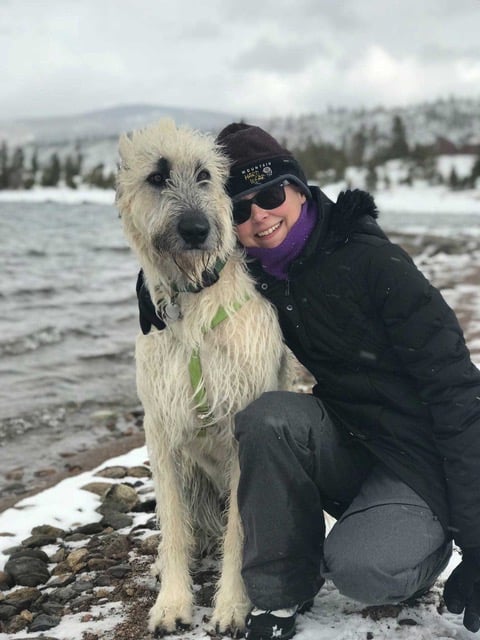 The author hugging her Irish Wolfhound by a snowy mountain lake