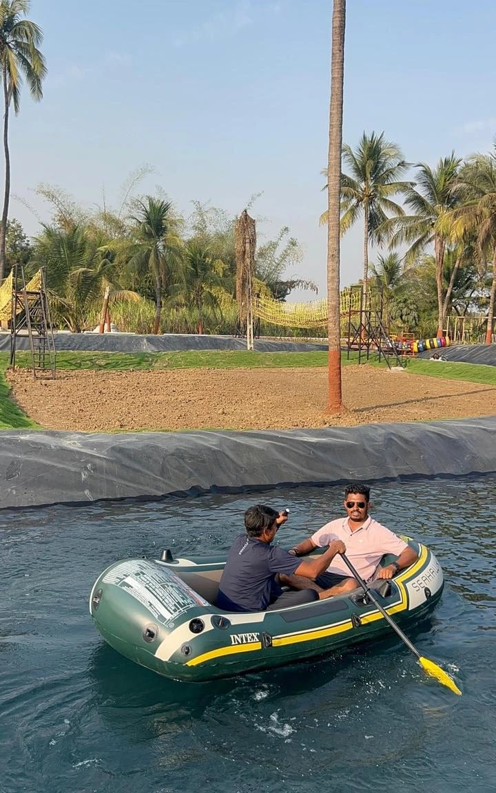 One-day picnic near Surat: Two people enjoying a relaxing boat ride on calm water, surrounded by palm trees