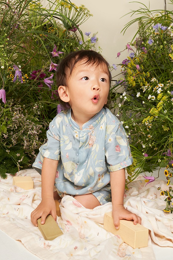 Bebê asiático veste macacão com estampa de arte original criada a mão da vida de um jardim