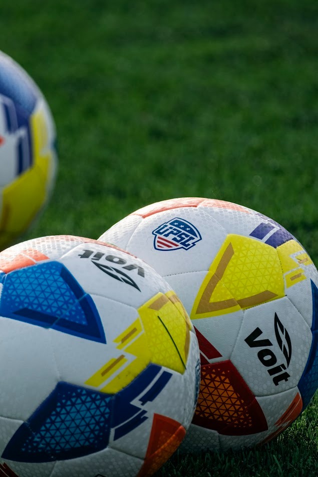 three soccer balls on a field with a soccer ball