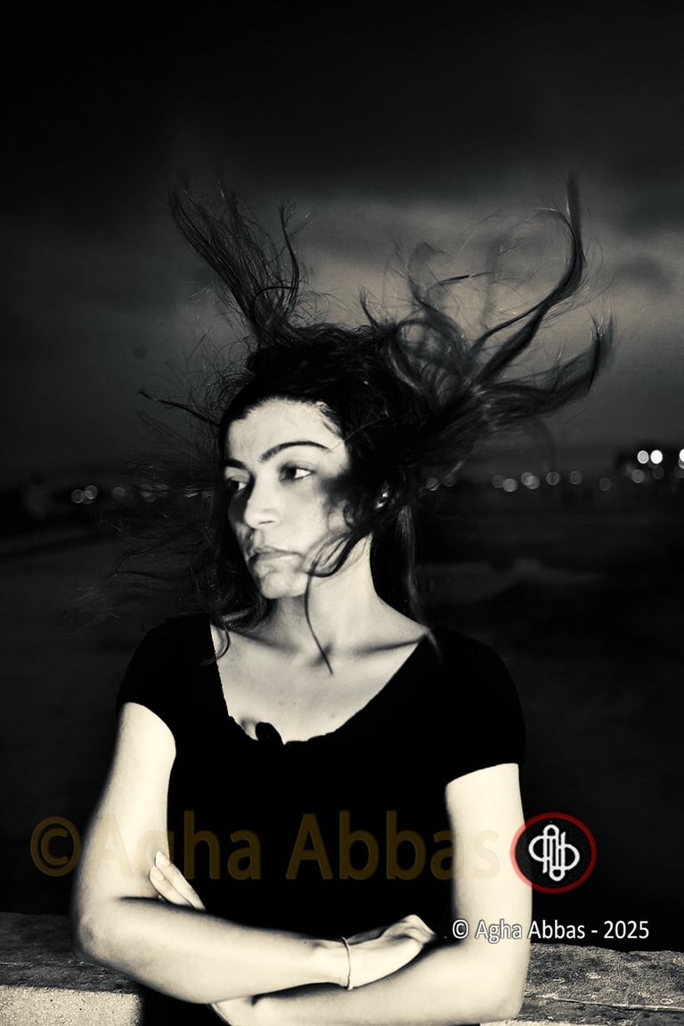 B&W photograph of a girl with the wind blowing her hair upwards. 