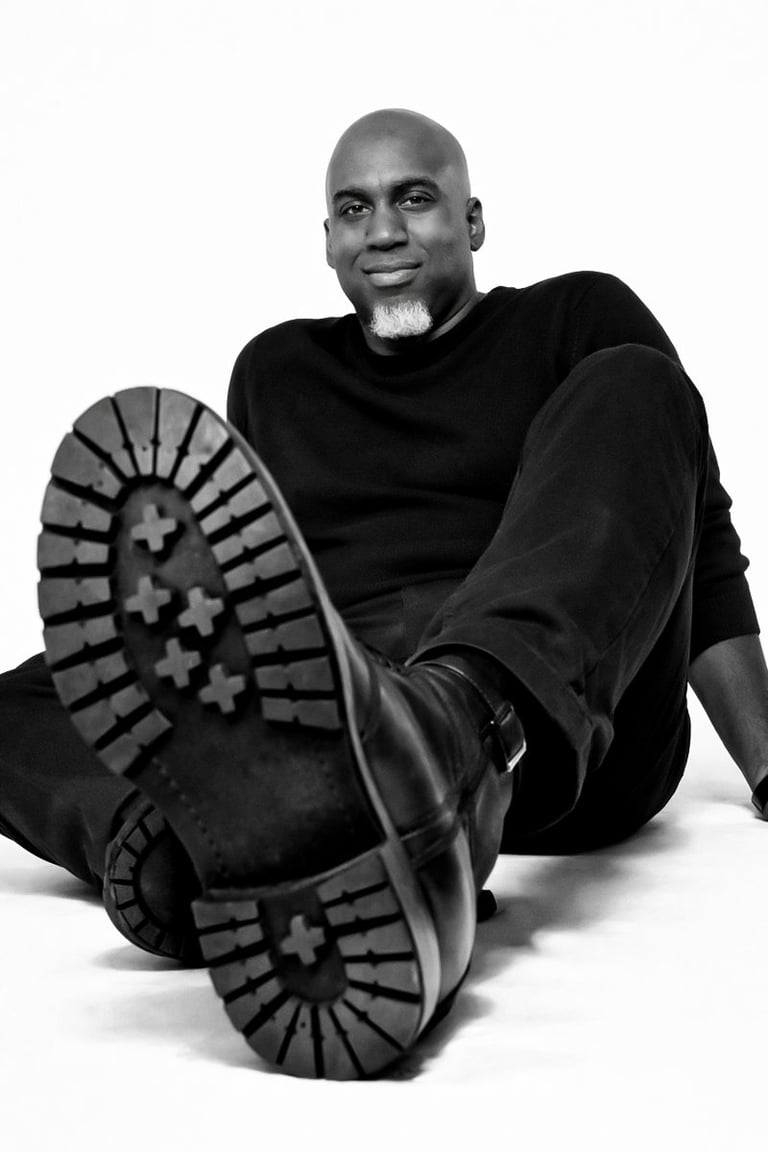 Lee A Jones in all black sitting on the floor with black boots