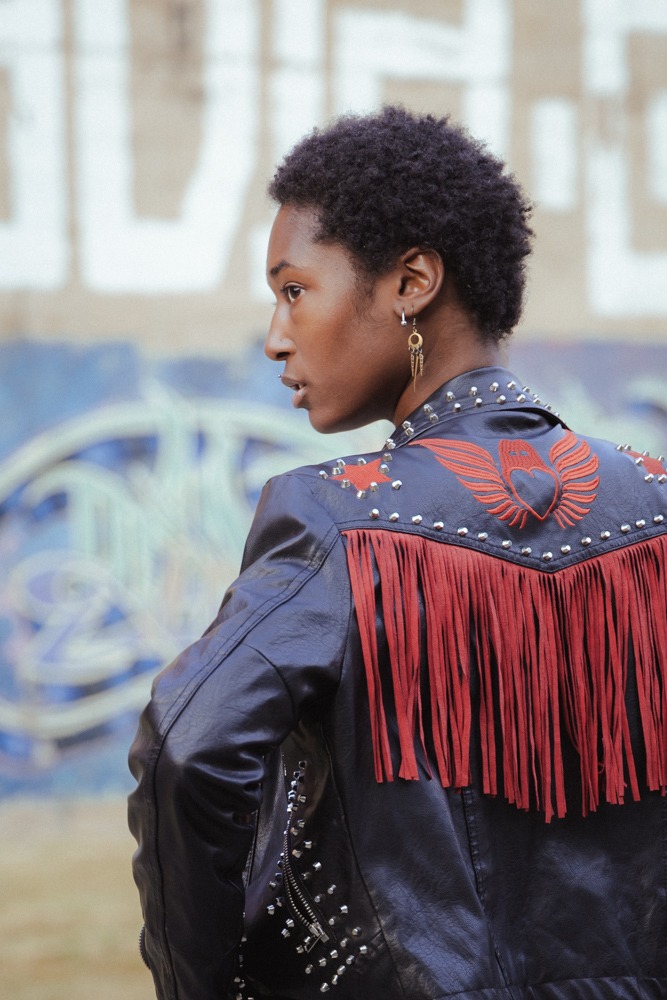 An over the shoulder shot of a model with cool earrings and a black leather jacket.