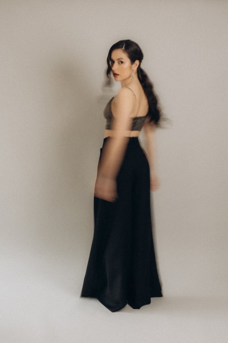 a woman in a black dress standing in front of a white wall