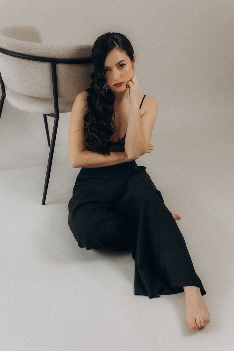 a woman sitting on a chair with her hand on her chin