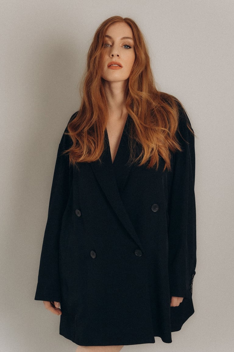 a woman with long and orange hair in a black coat.